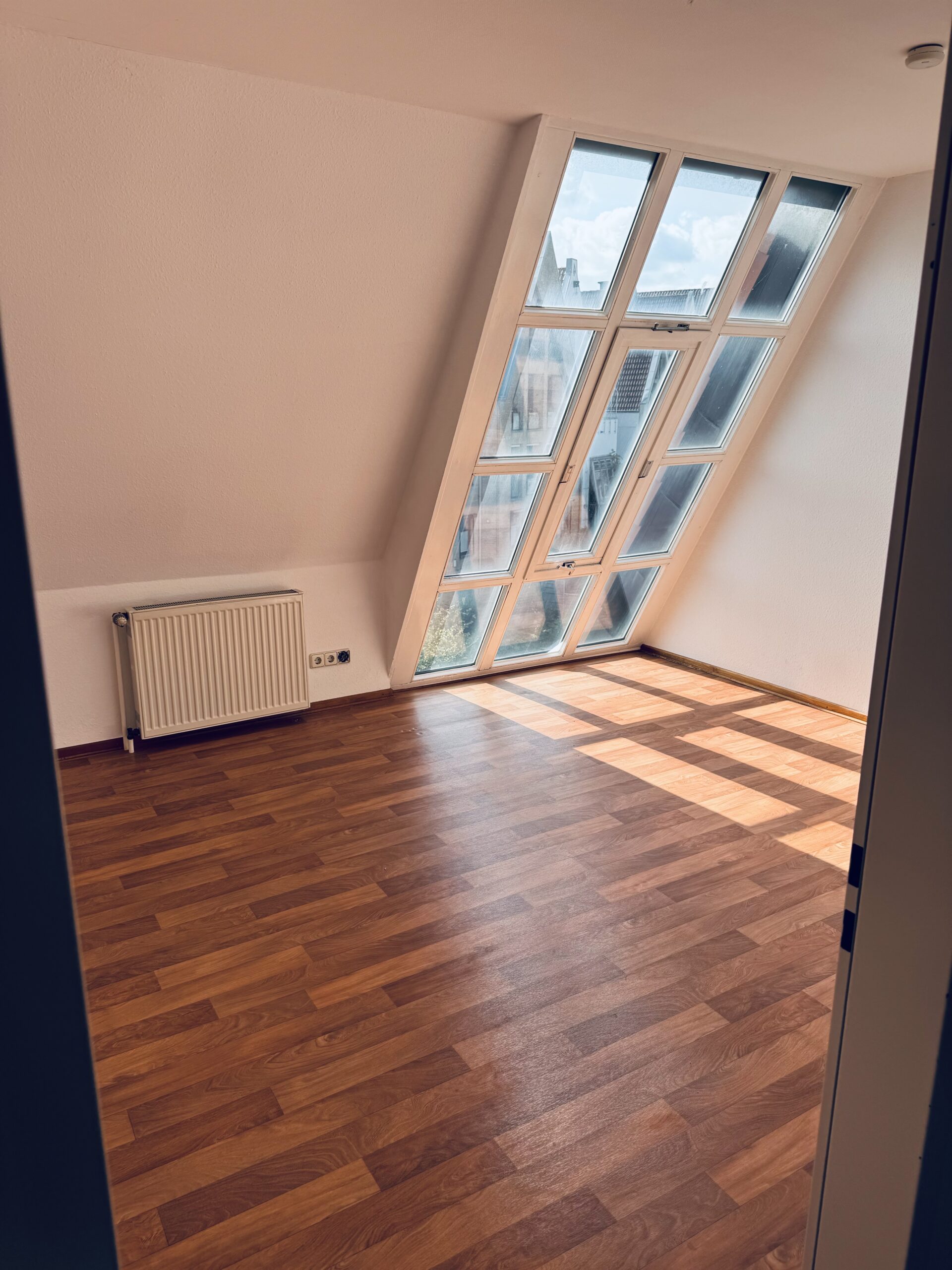 Zimmer mit großen Dachfenster und Holzboden